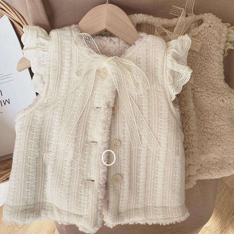 comme deux enfants Deze mouwloze crèmekleurige overgooier is perfect voor kindjes vanaf 1 jaar. Het heeft een warm teddy achterpand en een knoopsluiting. Het is niet alleen functioneel, maar ook super schattig!